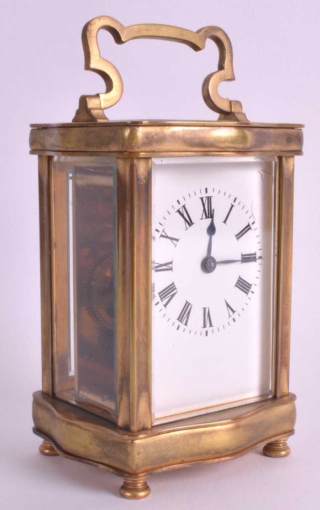 AN EARLY 20TH CENTURY BRASS BOUND CARRIAGE CLOCK with shaped handle, white enamel dial and black