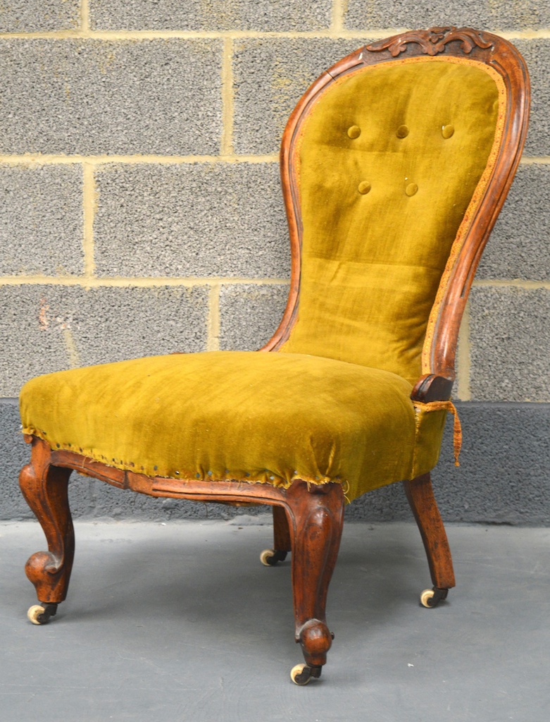 A VICTORIAN CARVED WALNUT NURSING CHAIR with olive green upholstery, upon carved cabriole legs.