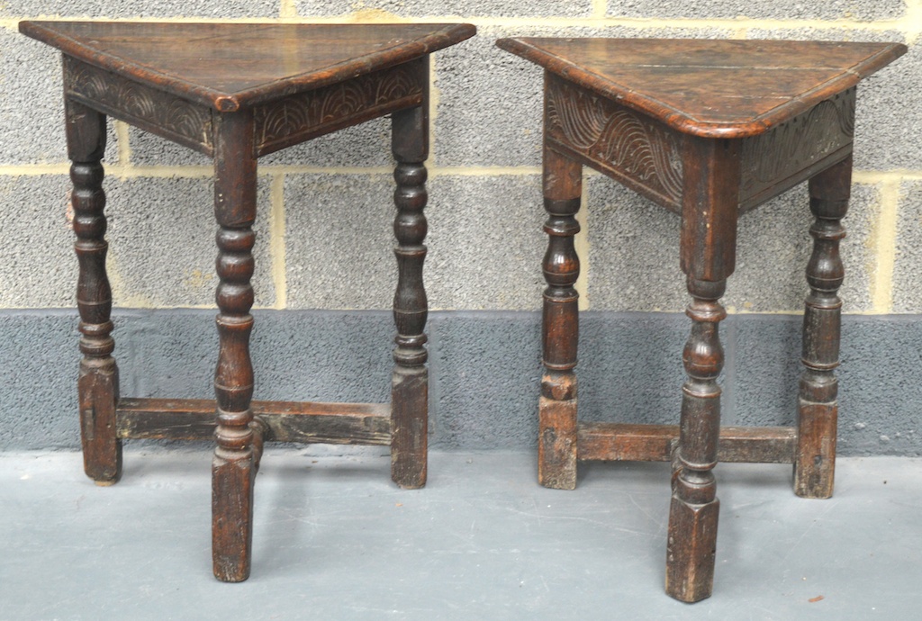 A NEAR PAIR OF EARLY 17TH CENTURY CARVED OAK TRIANGULAR TOP TABLES with triple plank tops, naively