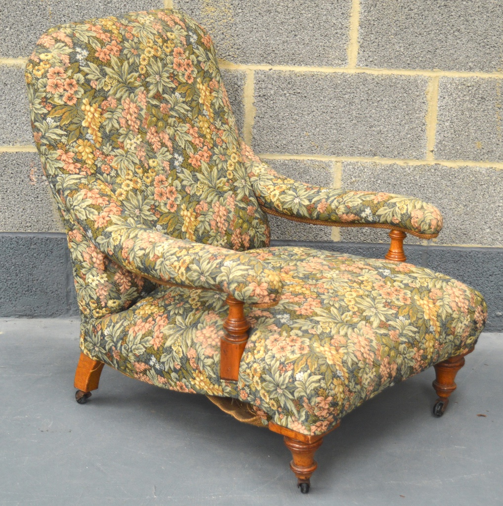 A LATE VICTORIAN CARVED WALNUT LIBRARY CHAIR with vibrant floral upholstery, long arms with pillar