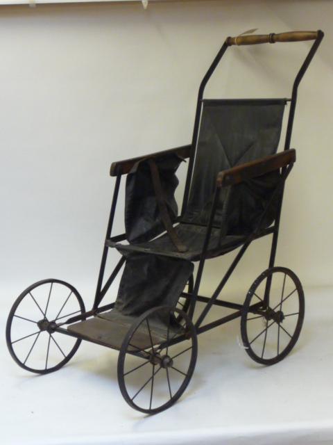 Dolls & Equipment. A folding pushchair for a large child, early 20th century, wrought iron frame and