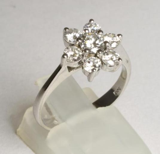 A DIAMOND FLOWER CLUSTER RING, the central brilliant cut stone of approximately 0.20cts and further