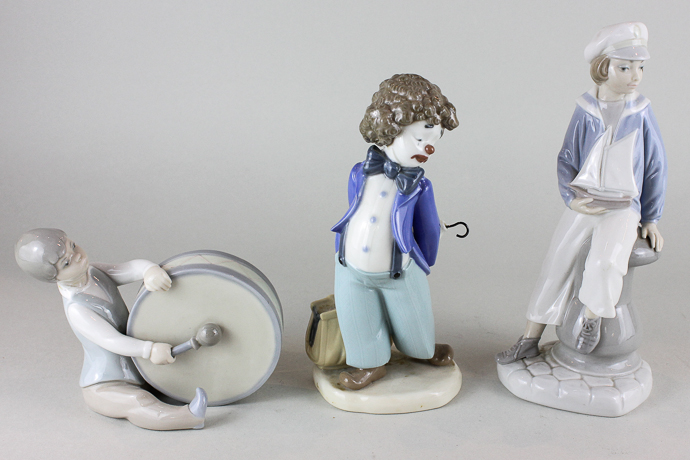 A Lladro porcelain figure ornament, boy with model yacht, another boy with drum and a Nao ornament