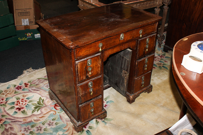 An early 18th century walnut desk with one long and six small drawers around recessed cupboard