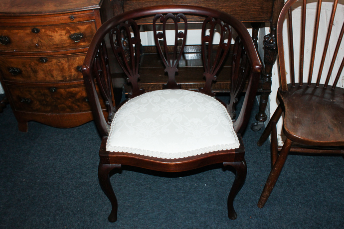 An early 20th century mahogany framed tub shaped chair with fretted back splats on slender