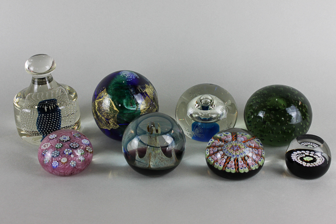 A collection of eight glass paperweights of various styles including a Caithness `Camelot`