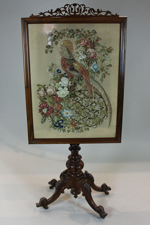 A Victorian mahogany fire screen with rectangular silk work panel of exotic birds on turned pedestal
