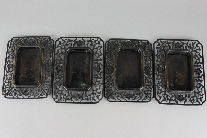Four Oriental bronze rectangular dishes/stands, each with wide pierced scroll, leaf and flower