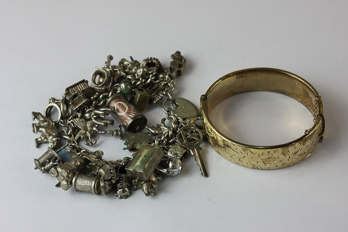 A silver charm bracelet and a gilt bangle,