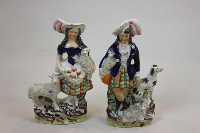 A pair of 19th century Staffordshire ornaments of Scotsman and lady both holding lambs, 24cm high