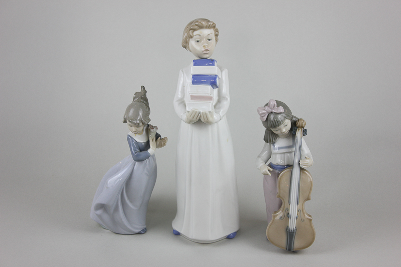 Three Nao porcelain ornaments, young girl with cello, girl with flowers and boy carrying books,