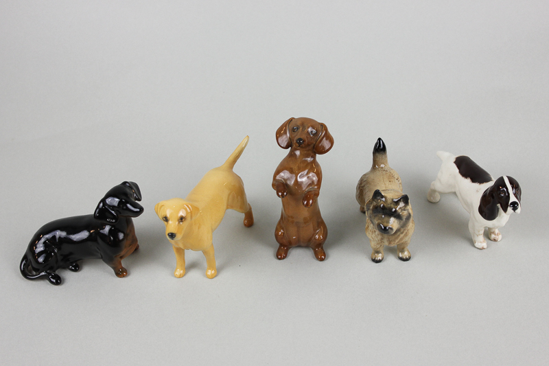 Five small Beswick dogs including seated Dachshund in black/tan, a begging Dachshund 1461 in tan