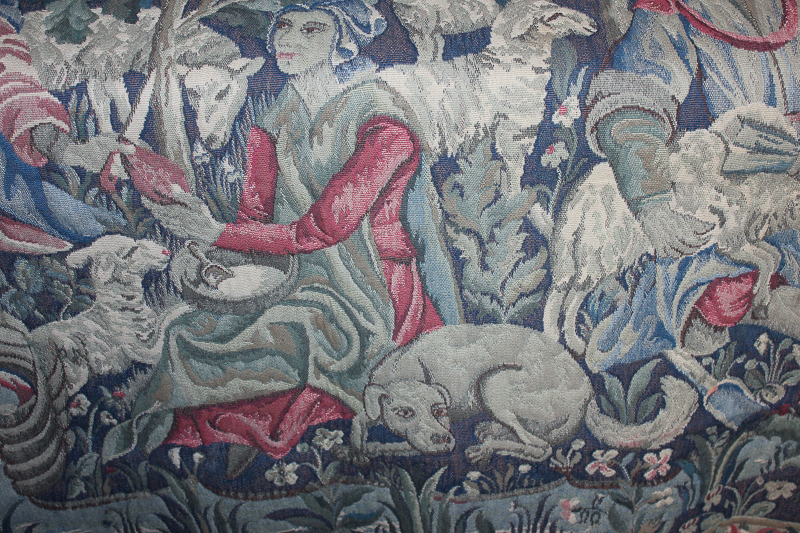 A machine woven tapestry depicting a woodland scene of shepherds, 135cm by 190cm
