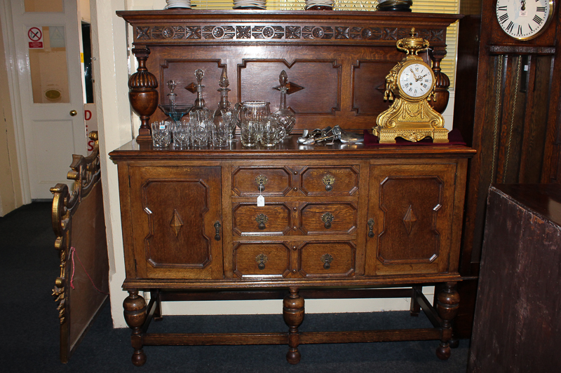 An early 20th century oak sideboard with three panelled drawers and two cupboards, on baluster