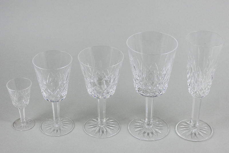 A part cut glass table set of drinking glasses, all with slice cut decoration on stemmed bases, to