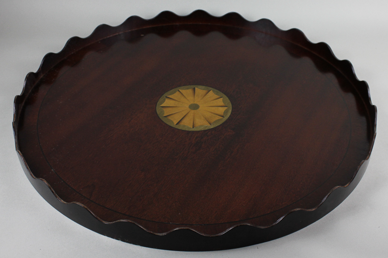 A circular mahogany tea tray with waved gallery border and `bats wing` inlaid roundel centre, 59cm