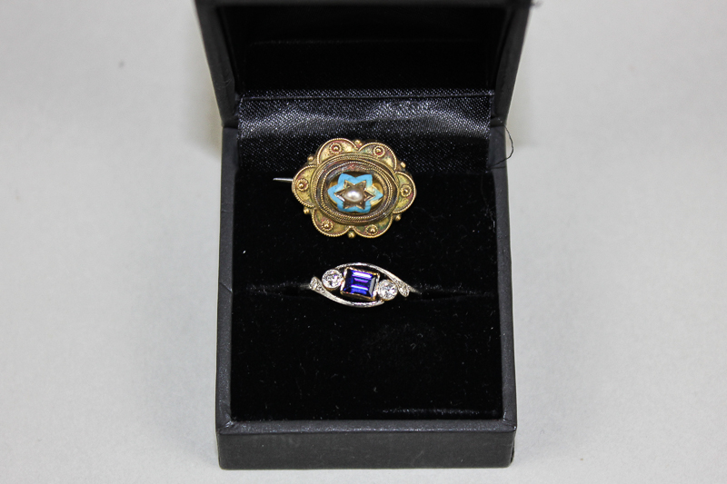 A diamond crossover ring rubover set with a central step cut blue stone in platinum and 18ct gold, a