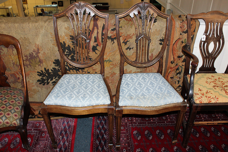A pair of Hepplewhite style mahogany dining chairs with shield shape backs, on square tapered legs