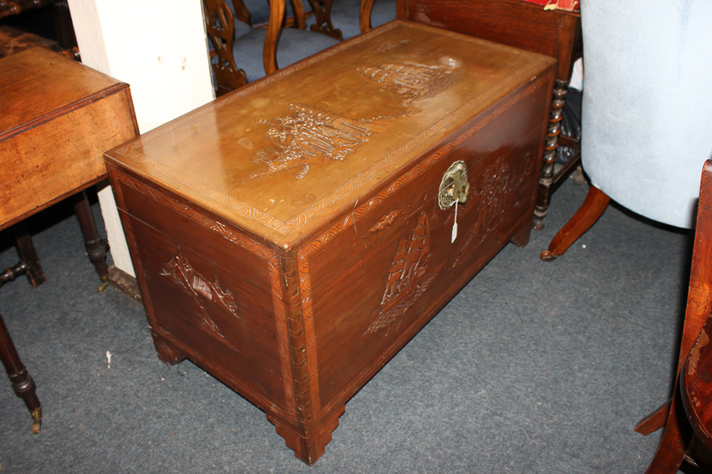 A 20th century Chinese export camphor wood chest with hinged top, the front and top with carved ship