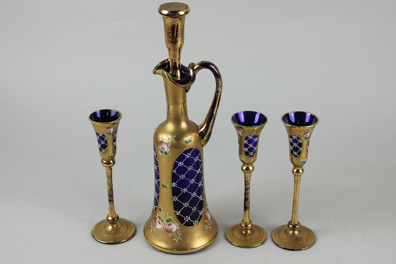 A Venetian blue glass liqueur decanter and three tall stemmed glasses, all richly decorated in