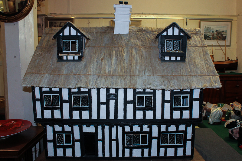 A Tudor style child`s dolls` house with `thatch` style roof and lift out front panels revealing