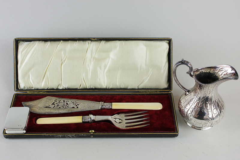 A pair of plated white handled fish servers in case; a plated cream jug and a pill box