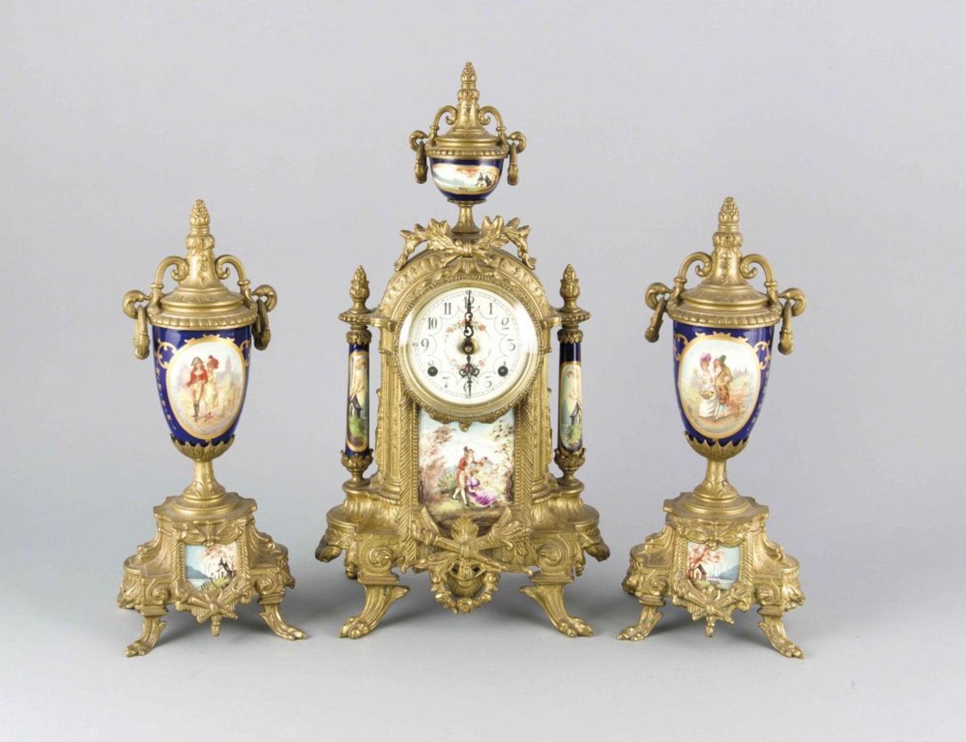 Uhrengarnitur, 3-tlg., 20. Jh., Bronze und Porzellan mit verschiedenen galanten Szenen, hinter