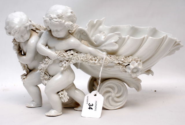 A C19TH GERMAN HARD PASTE BASKET IN THE FORM OF A SHELL PULLED BUY CHERUBS, 30CM LENGTH