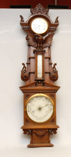 AN EDWARDIAN OAK CASED ANEROID BAROMETER WITH CARVED EAGLE MOTIF