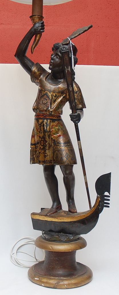 LAMP HOLDER FIGURE OF ETHNIC WARRIOR HOLDING PADDLE AND STANDING ON PART OF A CANOE