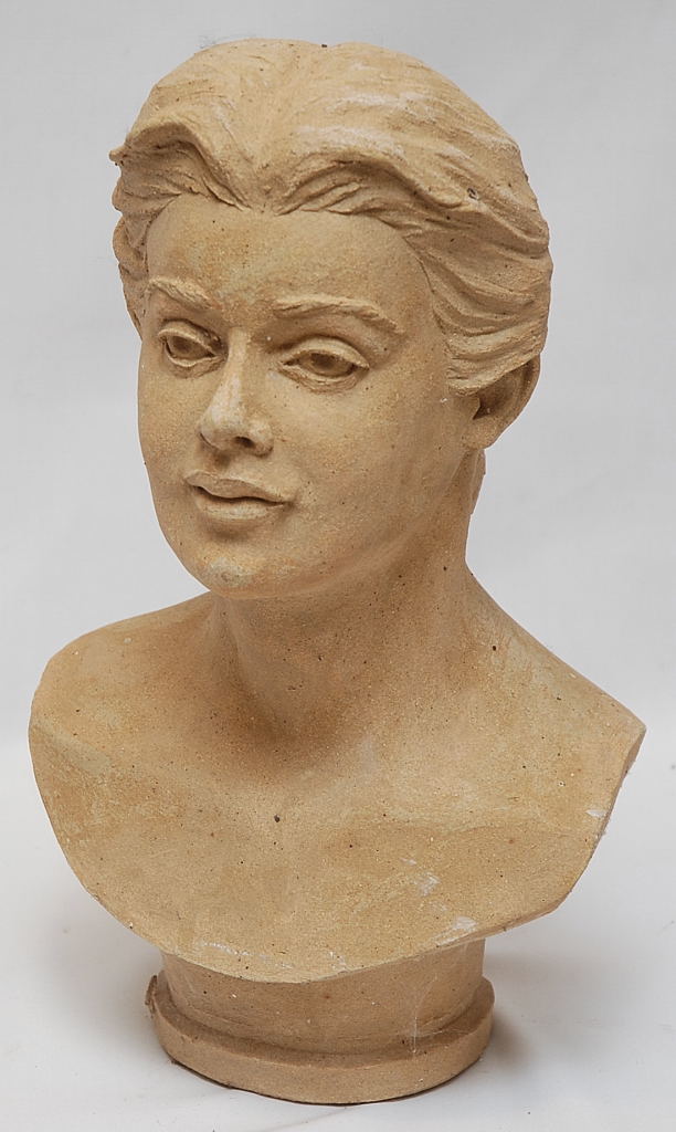 AN ART POTTERY BUST OF A WOMAN WITH A PLAIT IN HER HAIR BEARING SIGNATURE W.M. CANN