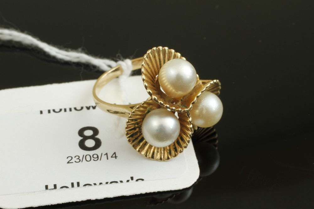 A three stone cultured pearl dress ring, in reeded cup mounts marked `K14`