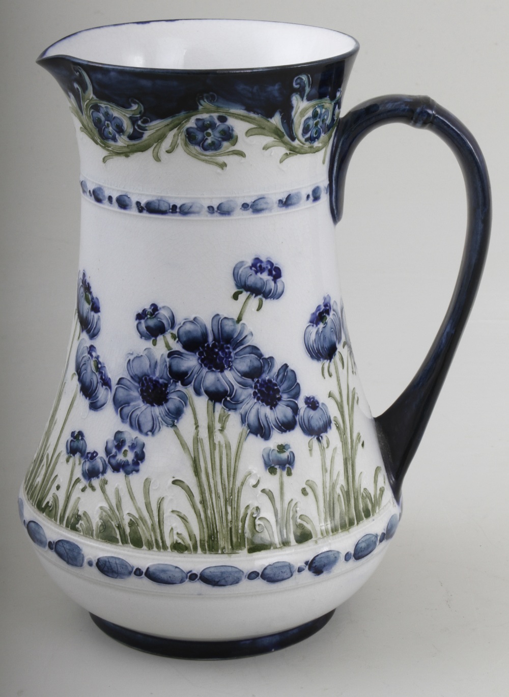 A MacIntyre `Poppy` pattern tube line baluster jug, decorated in blues and greens, on an ivory