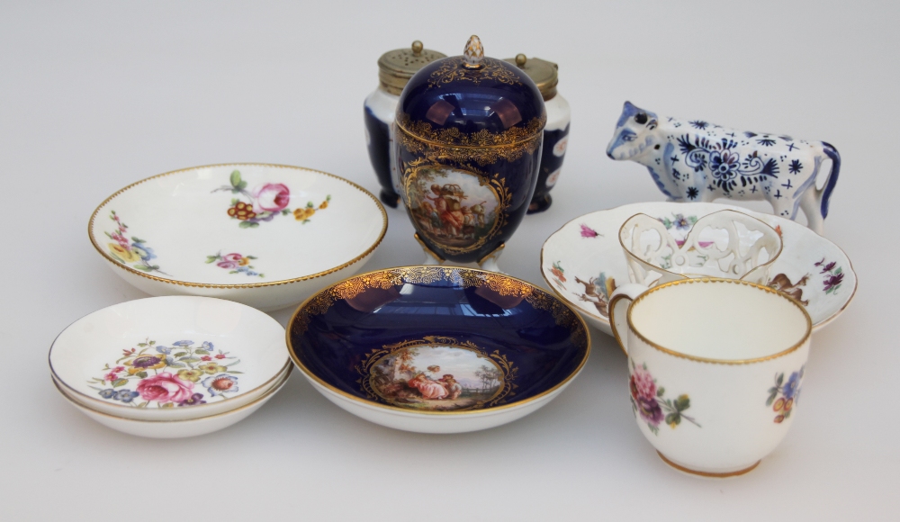 A Sèvres porcelain cup and saucer, painted with cut blooms on a white ground within gilt borders,