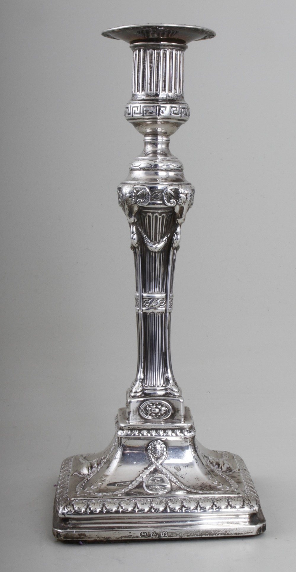 A George III silver candlestick, classical design, fluted and Greek key banded nozzle, rams heads