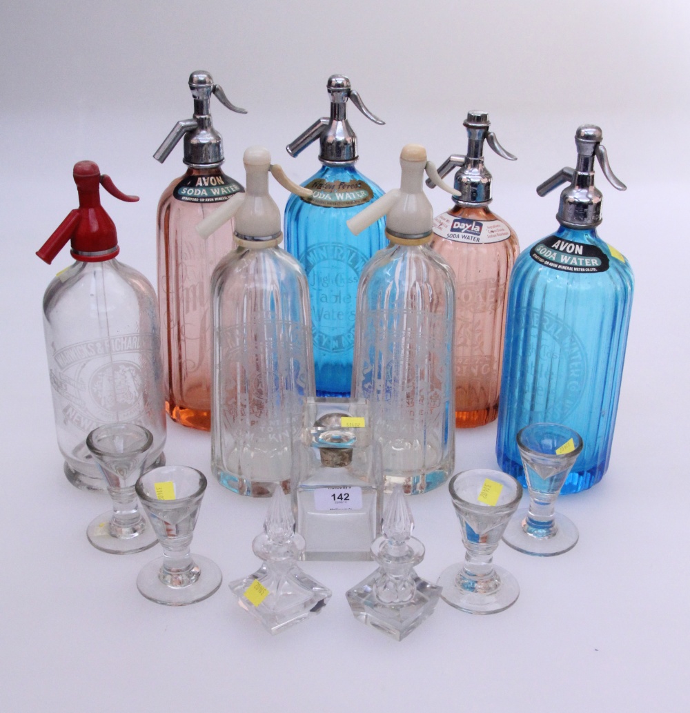 A collection of seven soda siphons, together with a  a pair of scent bottles with stoppers, one