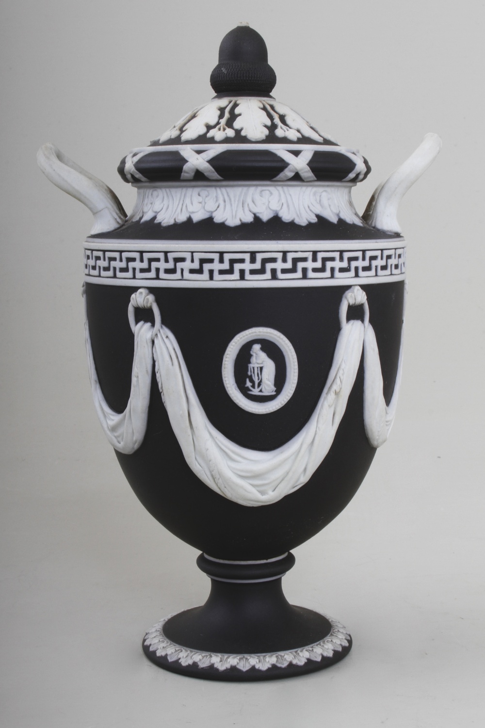 A Wedgwood black basalt classical two hand urn, with white Neo-classical appliques in the form of