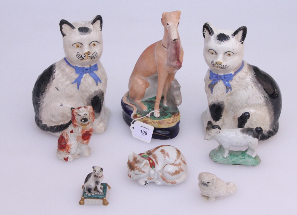 An unusual Victorian Staffordshire pottery seated long dog, with hare hanging from its jaws, on a