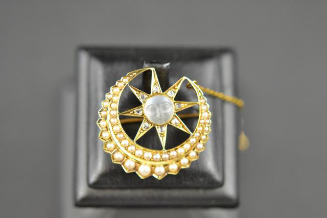 A yellow metal pearl and moonstone brooch of crescent moon and star form, the centre moonstone