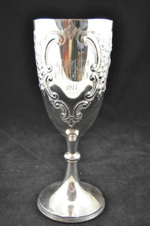 An embossed silver trophy with two cartouches, one inscribed, H27cm, Sheffield 1897, maker John