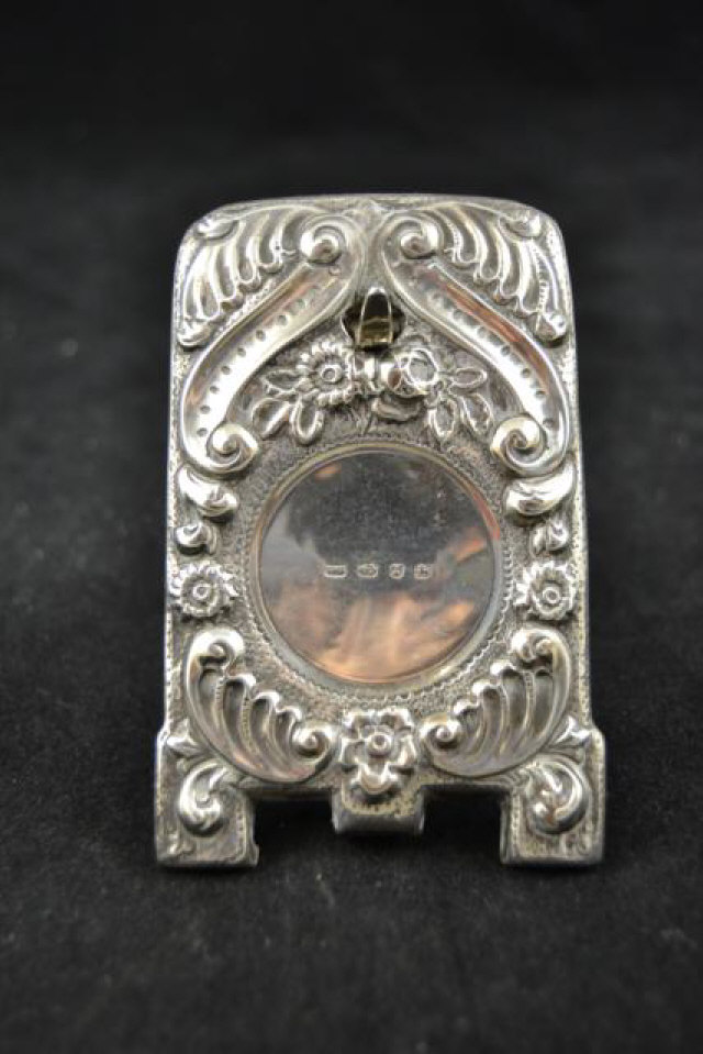 A late Victorian embossed silver watch stand with easel support, floral design, H10.5cm,