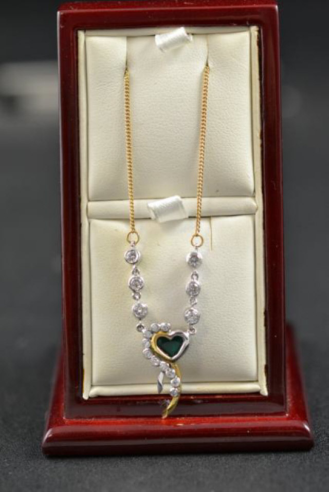 A yellow and white metal heart pendant set with emerald and diamonds, clarity P1, colour J-G, on