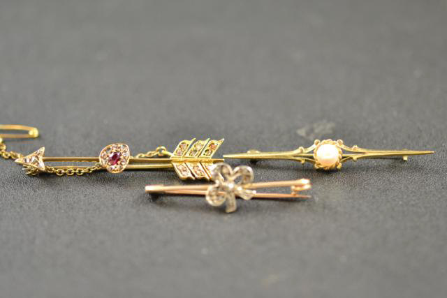 A 9ct gold diamond set bow brooch, a 9ct gold arrow brooch set with diamonds and ruby, together with