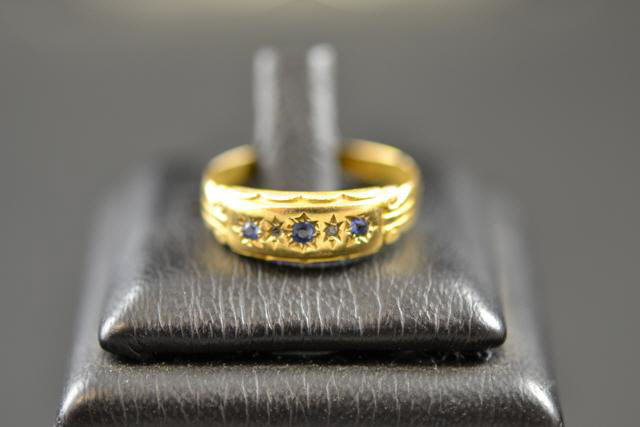 An 18ct gold ring with three gypsy set sapphires and two diamonds, size M 1/2 - approx gross