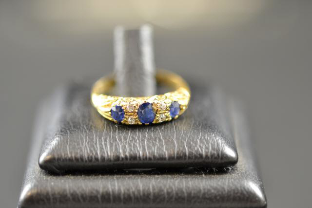 An 18ct gold ring set with three sapphires and four diamonds, London 1906/7, size J 1/2 - approx