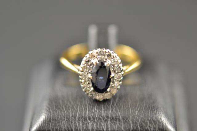 An 18ct gold ring set with central sapphire surrounded by diamonds, size O 1/2 - approx gross weight