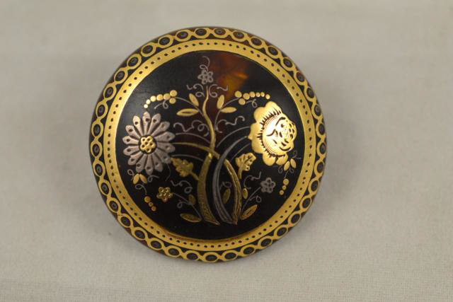 A 19th century circular tortoiseshell brooch decorated in gold and silver with floral design