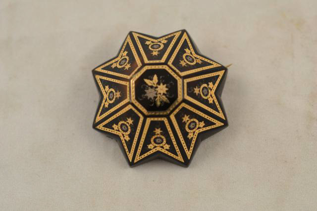 A 19th century star shaped tortoiseshell brooch decorated in gold with floral design - diam 4.2cm