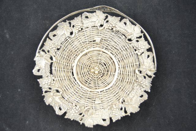 An unmarked white metal wirework bread/grape basket, embossed with wheat sheaves and fruiting vines,