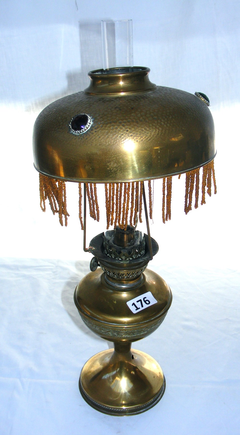 An Arabian brass oil lamp measuring 48cm tall, the shade inset with cabochon type inset stones.